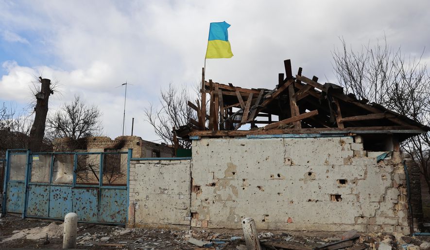 A Ukrainian flag is installed on an apartment building damaged by fighting between Russian and Ukrainian troops in a village of Lukyanivka, Kyiv region, Ukraine, Sunday, March 27, 2022. (AP Photo)