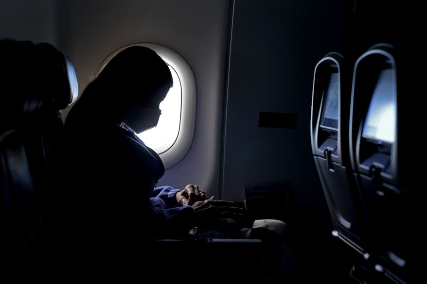In this Wednesday, Feb. 3, 2021, photo, a passenger wears a face mask she travels on a flight from Hartsfield-Jackson International Airport in Atlanta. In a lawsuit filed Tuesday, March 29, 2022, Florida and 20 other states are suing to halt the federal government's pandemic requirement that people wear masks on planes, trains and other public transport. (AP Photo/Charlie Riedel) **FILE**