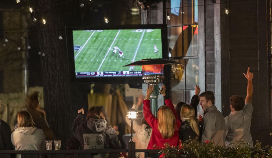 Alabama fans react as they watch television coverage of the College Football Playoff national championship game against Georgia, Monday, Jan. 10, 2022, in Tuscaloosa, Ala. Brookfield Business Partners is boosting its buyout offer for Nielsen Holdings, Tuesday, March 29, 2022, to about $16 billion after the TV ratings and marketing data company rejected a $9 billion takeover bid. (AP Photo/Vasha Hunt, File)