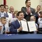 Florida Gov. Ron DeSantis displays the signed Parental Rights in Education, aka the Don&#39;t Say Gay bill, flanked by elementary school students during a news conference on Monday, March 28, 2022, at Classical Preparatory school in Shady Hills. (Douglas R. Clifford/Tampa Bay Times via AP)