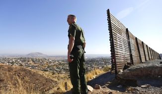 In this June 13, 2013 file photo, US Border Patrol agent Jerry Conlin looks out over Tijuana, Mexico, by the old border wall along the US - Mexico border, where it ends at the base of a hill in San Diego. (AP Photo/Gregory Bull, File)