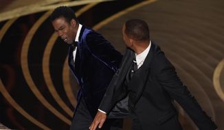 FILE - Will Smith, right, hits presenter Chris Rock on stage while presenting the award for best documentary feature at the Oscars on Sunday, March 27, 2022, at the Dolby Theatre in Los Angeles. The incident on Sunday has sparked debate about the appropriate ways for Black men to publicly defend Black women against humiliation and abuse. (AP Photo/Chris Pizzello, File)