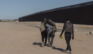 Nicaraguan migrants walk on the US-Mexico border, in Algodones, Baja California, Mexico, Dec. 2, 2021. The group walked into the U.S. and turned themselves over to the border patrol asking for asylum. The Biden administration has a draft plan to end sweeping asylum limits at the U.S.-Mexico border by May 23 that were put in place to prevent the spread of COVID-19, according to people familiar with the plans. (AP Photo/Felix Marquez, File)
