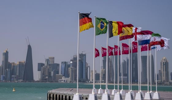 Flags of some of the qualified countries of the World Cup  wave at the seafront in Doha, Qatar, Tuesday, March 29, 2022. The draw for the World Cup will be held in Doha on April 1.(AP Photo/Darko Bandic)
