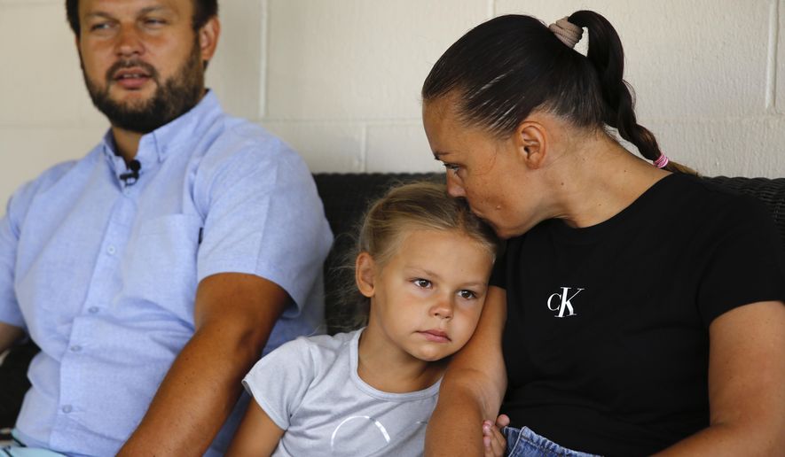 Vasyl Prishchak, left, is interviewed by The Associated Press as his wife, Marina, right, and daughter, Ksenia, 5, sit next to him at their temporary home in Kailua, Hawaii, Wednesday, March 23, 2022. The Prishchak family travelled to Hawaii for a long-awaited vacation on Feb. 16 and planned to return to Ukraine on March 7. But a week into their vacation, Russia invaded their country, leaving the family in shocked disbelief with no access to family, friends, money or their home. (AP Photo/Caleb Jones)