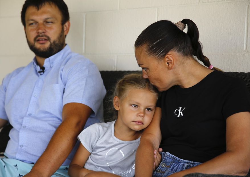 Vasyl Prishchak, left, is interviewed by The Associated Press as his wife, Marina, right, and daughter, Ksenia, 5, sit next to him at their temporary home in Kailua, Hawaii, Wednesday, March 23, 2022. The Prishchak family travelled to Hawaii for a long-awaited vacation on Feb. 16 and planned to return to Ukraine on March 7. But a week into their vacation, Russia invaded their country, leaving the family in shocked disbelief with no access to family, friends, money or their home. (AP Photo/Caleb Jones)
