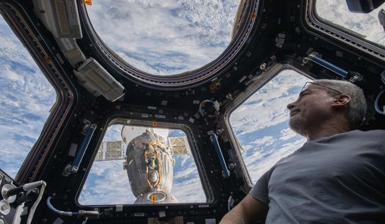 In this photo provided by NASA, U.S. astronaut and Expedition 66 Flight Engineer Mark Vande Hei peers at the Earth below from inside the seven-windowed cupola, the International Space Station&#39;s window to the world on Feb. 4, 2022. The Soyuz MS-19 crew ship is docked to the Rassvet module in the background. Vande Hei has made it through nearly a year in space, but in March 2022 faces what could be his trickiest assignment yet: riding a Russian capsule back to Earth in the midst of deepening tensions between the countries. (Kayla Barron/NASA via AP)
