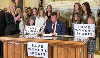 Oklahoma Gov. Kevin Stitt signs a bill in Oklahoma City on Wednesday, March 30, 2022, that prevents transgender girls and women from competing on female sports teams. Stitt signed the bill flanked by more than a dozen young female athletes, including his eighth-grade daughter Piper. (AP Photo/Sean Murphy)
