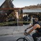 In this June 1, 2020, file photo, a cyclist passes burned-out businesses along East Lake Street that were destroyed in protests two nights earlier in Minneapolis. An external review of Minnesota&#39;s response to the civil unrest following the May 2020 killing of George Floyd found several weaknesses, including a lack of clear leadership early on as businesses were being destroyed and set ablaze, and a failure to discern peaceful from unlawful protesters. (AP Photo/John Minchillo, file)