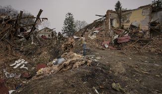 A man throws debris from buildings destroyed during fighting between Russian and Ukrainian forces in a large explosion crater outside Kyiv, Ukraine, Friday, April 1, 2022. (AP Photo/Vadim Ghirda)