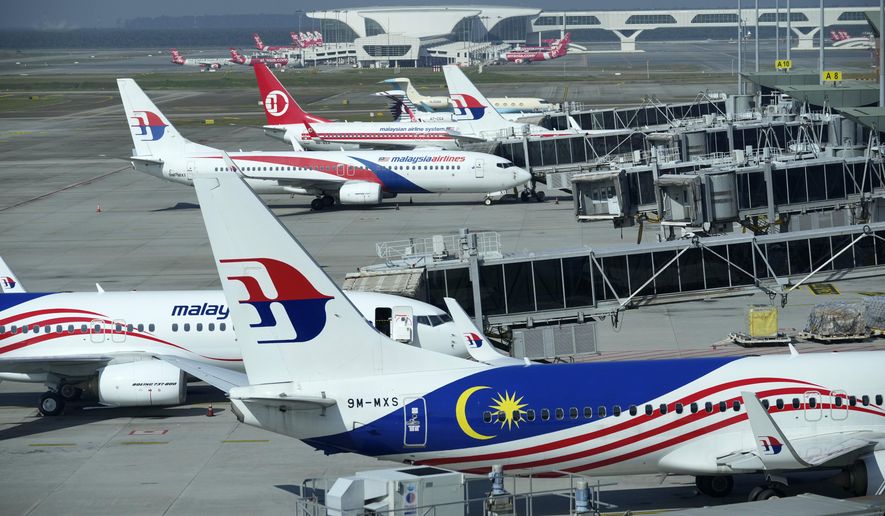 Malaysia Airlines planes taxi at terminal while uploading passengers at Kuala Lumpur International Airport in Sepang, Malaysia, Friday, April 1, 2022. (AP Photo/Vincent Thian)