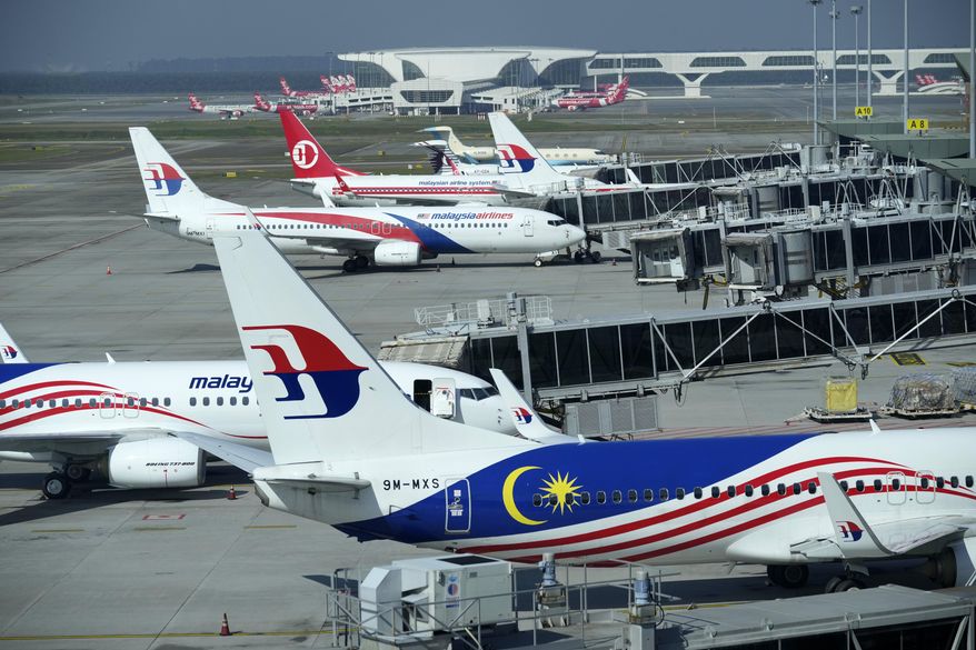 Malaysia Airlines planes taxi at terminal while uploading passengers at Kuala Lumpur International Airport in Sepang, Malaysia, Friday, April 1, 2022. (AP Photo/Vincent Thian)