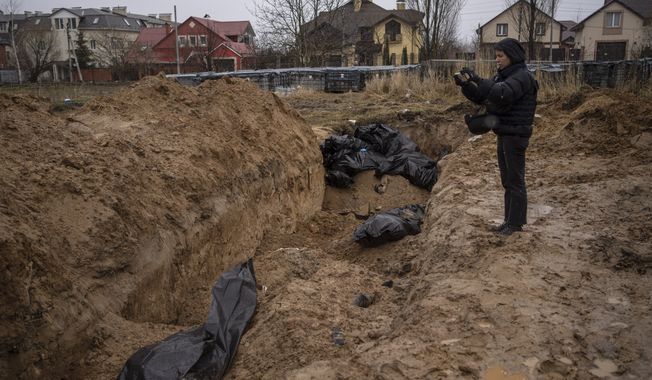 A journalist takes video of a mass grave in Bucha, on the outskirts of Kyiv, Ukraine, Sunday, April 3, 2022. (AP Photo/Rodrigo Abd)