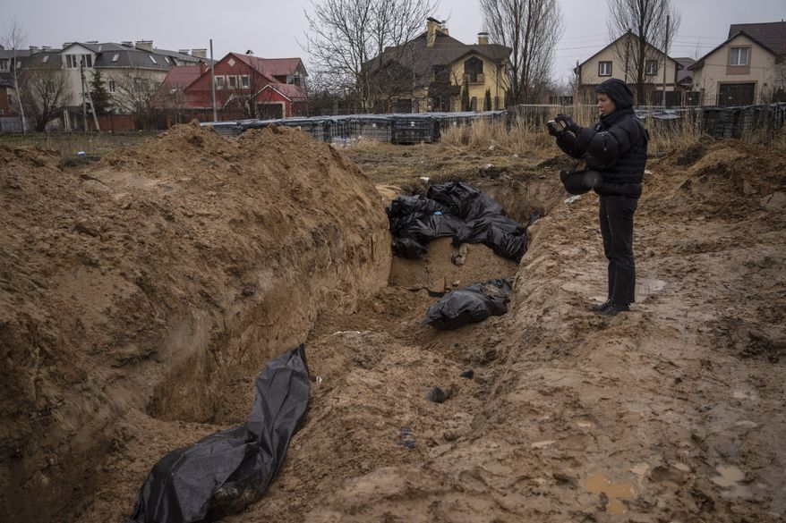 A journalist takes video of a mass grave in Bucha, on the outskirts of Kyiv, Ukraine, Sunday, April 3, 2022. (AP Photo/Rodrigo Abd)