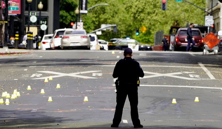 A Sacramento City Police Officer stands near a field of evidence markers after a mass shooting In Sacramento, Calif. April 3, 2022.  (AP Photo/Rich Pedroncelli)