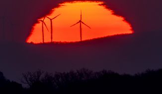 Wind turbines stand in front of the rising sun in Frankfurt, Germany, Friday, March 11, 2022. A United Nation-backed panel plans to release a highly anticipated scientific report on Monday, April 4, 2022, on international efforts to curb climate change before global temperatures reach dangerous levels. (AP Photo/Michael Probst, File)