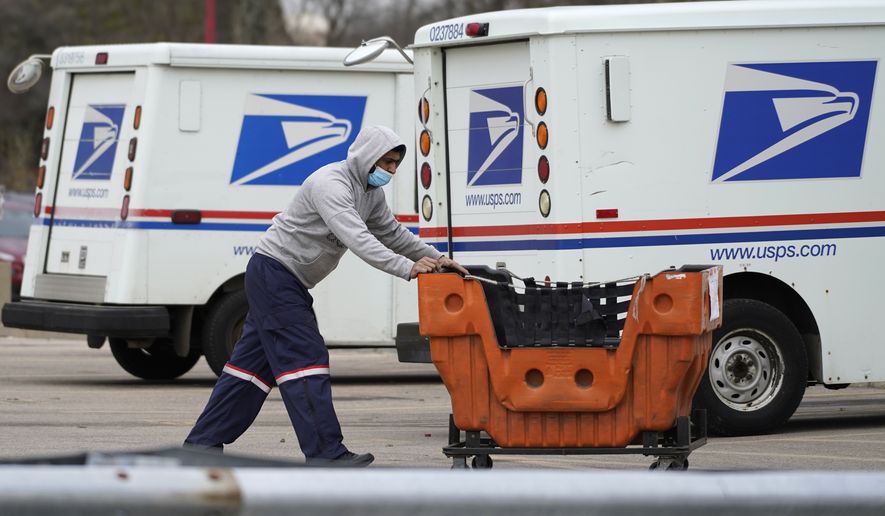 A USPS employee works outside post office in Wheeling, Ill., Dec. 3, 2021. A government watchdog said says the U.S. Postal Service&#39;s environmental evaluation used for purchases of next-generation delivery vehicles relied on some false assumptions. Jill Naamane from the Government Accountability Office told the House Oversight Committee on Tuesday that the analysis used to determine the mix of gas- and electric-vehicles overstated maintenance costs of electric vehicles and relied on gas prices that dont reflect the current reality. (AP Photo/Nam Y. Huh, File)