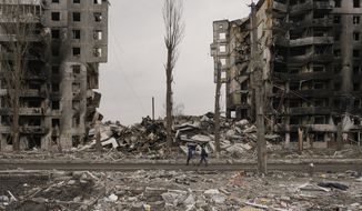 People walk by an apartment building destroyed during fighting between Ukrainian and Russian forces in Borodyanka, Ukraine, Tuesday, April 5, 2022. Ukrainian President Volodymyr Zelenskyy accused Russian troops of gruesome atrocities in Ukraine and told the U.N. Security Council on Tuesday that those responsible should immediately be brought up on war crimes charges in front of a tribunal like the one set up at Nuremberg after World War II.(AP Photo/Vadim Ghirda)
