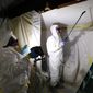 FILE - Asbestos Removal Technologies Inc., job superintendent Ryan Laitila, right, sprays amended water as job forman Megan Eberhart holds a light during asbestos abatement in Howell, Mich., Oct. 18, 2017. The Environmental Protection Agency on Tuesday, April 5, 2022, proposed a rule to finally ban asbestos, a carcinogen that is still used in some chlorine bleach, brake pads and other products and kills thousands of Americans every year. (AP Photo/Paul Sancya, File)