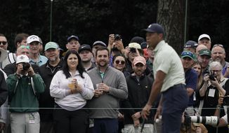 Spectators watch Tiger Woods on the driving range during a practice round for the Masters golf tournament on Tuesday, April 5, 2022, in Augusta, Ga. (AP Photo/Charlie Riedel)
