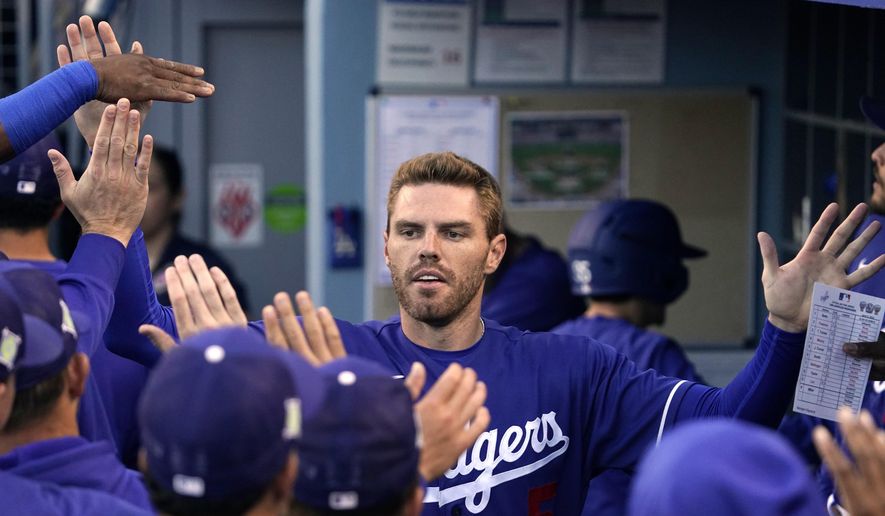Los Angeles Dodgers&#x27; Freddie Freeman is congratulated by teammates in the dugout after scoring on a double by Trea Turner during the first inning of a spring training baseball game against the Los Angeles Angels Tuesday, April 5, 2022, in Los Angeles. (AP Photo/Mark J. Terrill) **FILE**