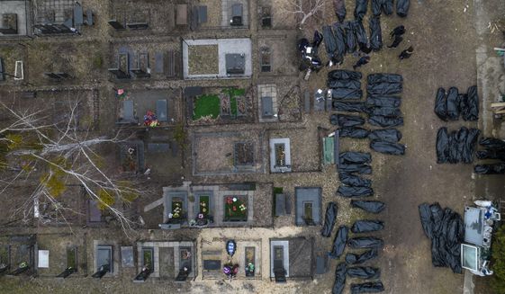 Policemen work to identify civilians who were killed during the Russian occupation in Bucha, Ukraine, on the outskirts of Kyiv, before sending the bodies to the morgue, Wednesday, April 6, 2022. (AP Photo/Rodrigo Abd)
