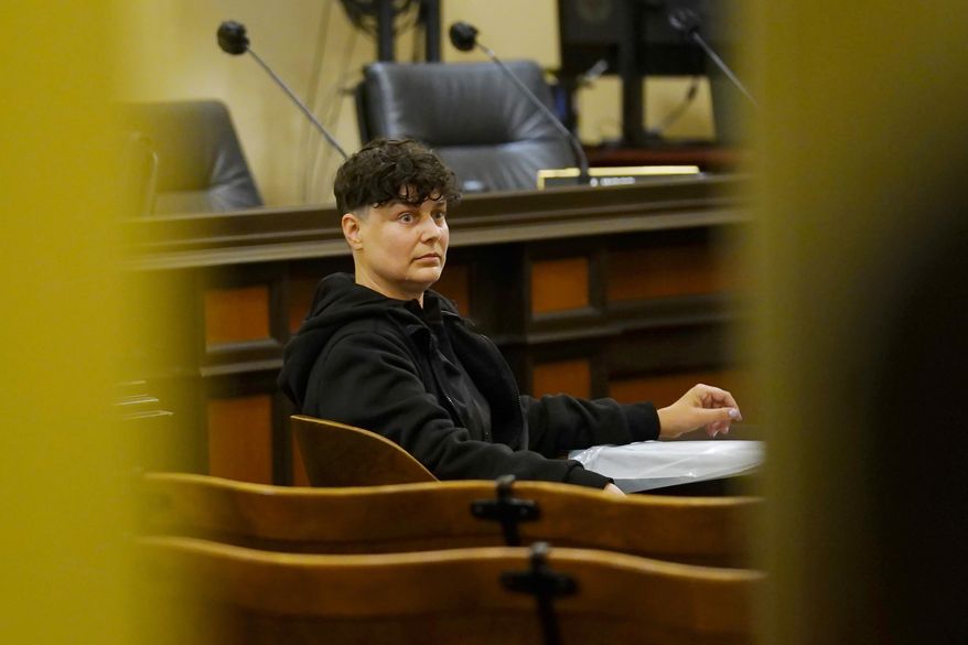 Carla Cabral sits with her left hand glued to a table, disrupting a hearing of the Assembly Agriculture Committee in Sacramento, Calif., on Wednesday, April 6, 2022. Cabral is an organizer with the animal rights group Direct Action Everywhere and wanted to tell the committee how upset she was that they were not voting on a bill proposing a moratorium on new factory farms. Lawmakers moved to another room to finish the hearing. After Paramedics freed Cabral's hand from the table, she was escorted out of the Capitol by the California Highway Patrol. She was not arrested or issued a citation. (AP Photo/Rich Pedroncelli)