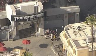 In this still image provided by ABC7 Los Angeles,  people stand near the Transformers ride at Universal Studios Hollywood in Los Angeles on Thursday, April 7, 2022.  A power outage left nearly a dozen people stranded on a ride until crews rescued them, Los Angeles authorities said. Emergency crews were called to the park&#39;s Transformers ride around 3:45 p.m. Thursday after 11 people got stuck on the indoor ride, according to the Los Angeles County Fire Department.(ABC7 Los Angeles via AP)