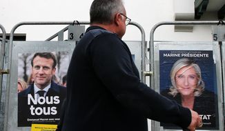 A man walks past presidential campaign posters of french president Emmanuel Macron and centrist candidate for reelection and french far-right presidential candidate Marine Le Pen in Anglet, southwestern France, Wednesday, April 8, 2022. France&#39;s first round of the presidential election takes place on April 10, with a presidential runoff on April 24 if no candidate wins outright. (AP Photo/Bob Edme)