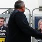 A man walks past presidential campaign posters of french president Emmanuel Macron and centrist candidate for reelection and french far-right presidential candidate Marine Le Pen in Anglet, southwestern France, Wednesday, April 8, 2022. France&#39;s first round of the presidential election takes place on April 10, with a presidential runoff on April 24 if no candidate wins outright. (AP Photo/Bob Edme)