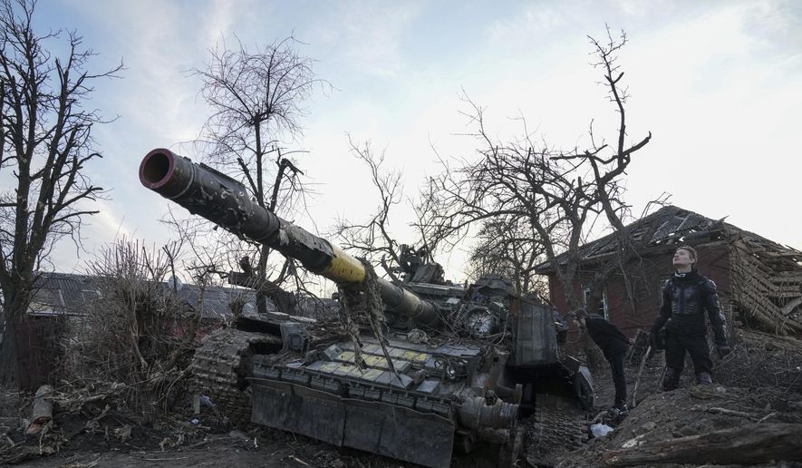 Men stand next to a destroyed tank in Chernihiv, Ukraine, Thursday, April 7, 2022. (AP Photo/Evgeniy Maloletka) ** FILE **