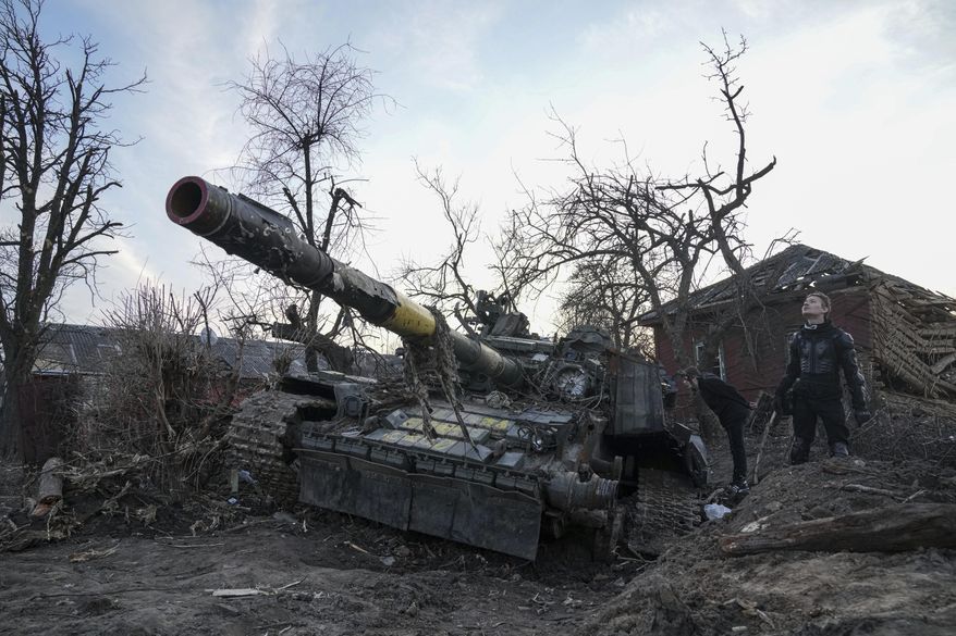 Men stand next to a destroyed tank in Chernihiv, Ukraine, Thursday, April 7, 2022. (AP Photo/Evgeniy Maloletka) ** FILE **