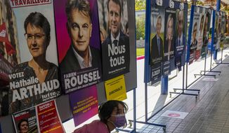 A girl walks past presidential campaign posters at a school working as a polling station for French citizens who living in Chile to vote one day ahead of France&#x27;s general elections in Santiago, Chile, Saturday, April 9, 2022. (AP Photo/Esteban Felix)