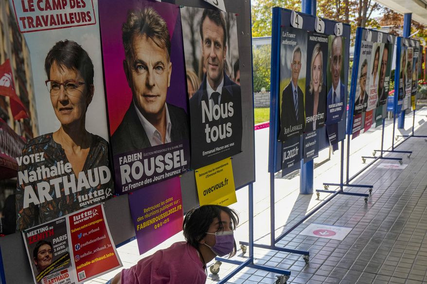 A girl walks past presidential campaign posters at a school working as a polling station for French citizens who living in Chile to vote one day ahead of France&#39;s general elections in Santiago, Chile, Saturday, April 9, 2022. (AP Photo/Esteban Felix)