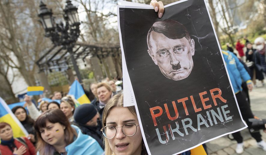 "Putler Ukraine" is written on the poster under a head, which is supposed to represent a mixture of German dictator Adolf Hitler and Russian President Vladimir Putin, displayed at a demonstration directed against the pro-Russian rally taking place at the same time in Frankfurt, Germany, Sunday, April 10, 2022. The police accompanied the rally with several hundred units. The demonstration was announced under the slogan "Against agitation and discrimination of Russian-speaking fellow citizens/Against war -— For peace". (Boris Roessler/dpa via AP) ** FILE **