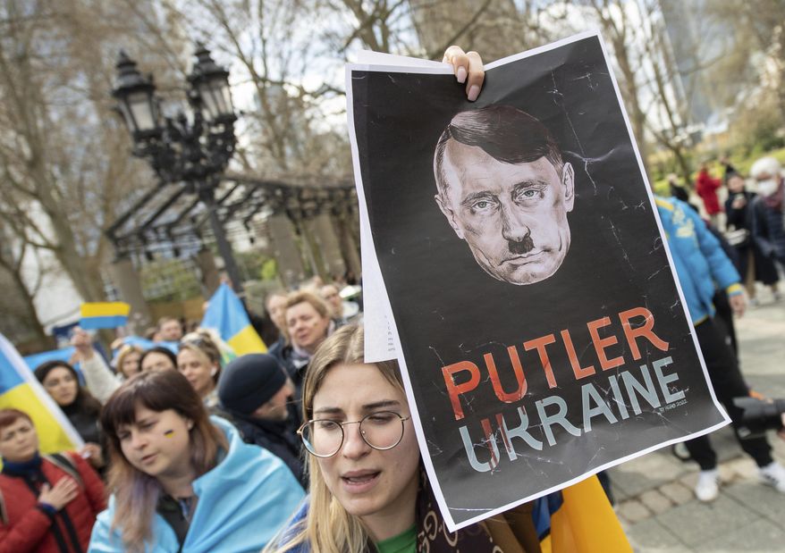 "Putler Ukraine" is written on the poster under a head, which is supposed to represent a mixture of German dictator Adolf Hitler and Russian President Vladimir Putin, displayed at a demonstration directed against the pro-Russian rally taking place at the same time in Frankfurt, Germany, Sunday, April 10, 2022. The police accompanied the rally with several hundred units. The demonstration was announced under the slogan "Against agitation and discrimination of Russian-speaking fellow citizens/Against war -— For peace". (Boris Roessler/dpa via AP) ** FILE **