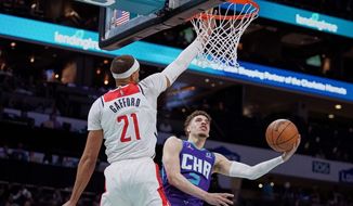 Charlotte Hornets guard LaMelo Ball, right, drives to the basket around Washington Wizards center Daniel Gafford (21) during the first half of an NBA basketball game on Sunday, April 10, 2022, in Charlotte, N.C. (AP Photo/Rusty Jones)