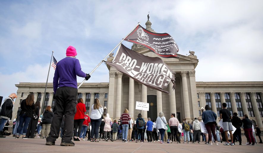 A person holds flags during the Bans Off Oklahoma Rally on the steps on Oklahoma state Capitol in Oklahoma City, Tuesday, April, 5, 2022. (Sarah Phipps/The Oklahoman via AP)