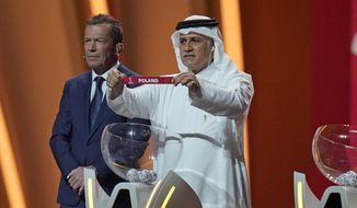 Former Qatari soccer international Adel Ahmed MalAllah holds up the name of Poland as he assists in the 2022 soccer World Cup draw at the Doha Exhibition and Convention Center in Doha, Qatar, Friday, April 1, 2022. (AP Photo/Darko Bandic) **FILE**