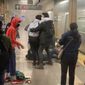 This photo provided by Will B Wylde,  a person is aided outside a subway car in the Brooklyn borough of New York, Tuesday, April 12, 2022. A gunman filled a rush-hour subway train with smoke and shot multiple people Tuesday, leaving wounded commuters bleeding on a Brooklyn platform as others ran screaming, authorities said. Police were still searching for the suspect. (Will B Wylde via AP)