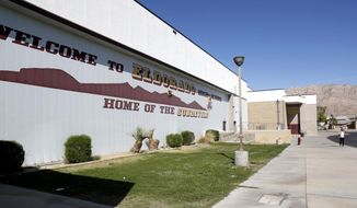 A person walks outside Eldorado High School in Las Vegas Friday, April 8, 2022. A student who attacked a teacher in a classroom at the school is facing counts of attempted murder and sexual assault, according to Las Vegas Metro Police. (Steve Marcus/Las Vegas Sun via AP) ** FILE **