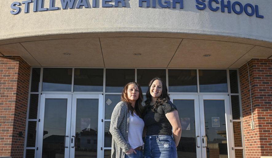 Angela Morgan, left, and her daughter Sidney McLaughlin stand in front of Stillwater High School in Stillwater, Okla., March 15, 2022. Nearly 50 years after Congress passed the sweeping law that guarantees equity in “any education program or activity receiving Federal financial assistance,” including high school athletics, girls are stuck in an imperfect system that continues to favor boys. (Jason Elquist/Elm Tree Photo via AP) **FILE**