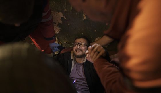 Vadim Krikun is treated in the hallway of his apartment building after a Russian attack in Kharkiv, Ukraine, Friday, April 15, 2022. (AP Photo/Felipe Dana)