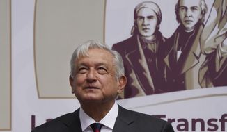 Mexican President Andres Manuel Obrador smiles as people applaud after the playing of the national anthem at the end of an event where he delivered a speech on economic figures, in Mexico City, Tuesday, April 12, 2022. (AP Photo/Marco Ugarte)