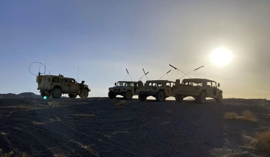 Army vehicles on the ridge, as soldiers from the 2nd Brigade, 1st Cavalry Division, prepare to attack the enemy in the town nearby, during an early morning training exercise at the National Training Center at Fort Irwin, Calif., on April 12, 2022. (AP Photo/Lolita C. Baldor) **FILE**