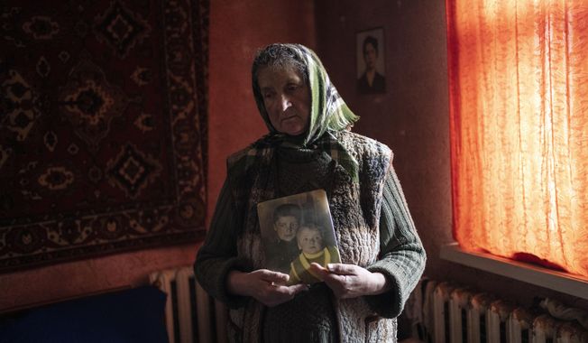 Nadiya Trubchaninova, 70, stands in her bedroom holding a portrait of her sons Oleg Trubchaninov, 46, and Vadym, 48, who was killed by Russian soldiers last March 30 in Bucha, in the outskirts of Kyiv, Ukraine, Thursday, April 14, 2022. This is not where Nadiya Trubchaninova thought she would find herself at 70 years of age, hitchhiking daily from her village to the shattered town of Bucha trying to bring her son&#x27;s body home for burial. (AP Photo/Rodrigo Abd, File)
