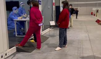 In this image taken from video provided by Beibei, who asked to be identified only by her given name, residents seek medical help at the National Exhibition and Convention Center which converted to a quarantine facility set up for people who test positive but have few or no symptoms on April 15, 2022, in Shanghai. (Beibei via AP)