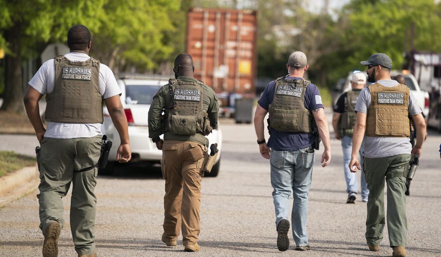 Members of the U.S. Marshals fugitive task force walk down a street near Columbiana Centre mall in Columbia, S.C., following a shooting, Saturday, April 16, 2022. (AP Photo/Sean Rayford)