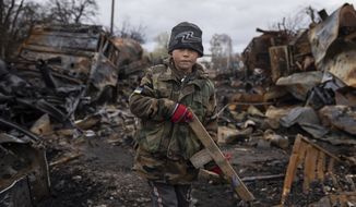 Yehor, 7, stands holding a wooden toy rifle next to destroyed Russian military vehicles near Chernihiv, Ukraine, Sunday, April 17, 2022. Witnesses said multiple explosions believed to be caused by missiles struck the western Ukrainian city of Lviv early Monday as the country was bracing for an all-out Russian assault in the east. (AP Photo/Evgeniy Maloletka)