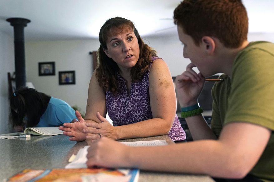 Jennifer Osgood, center, teaches her son, Noah, 12, while reviewing school work at their home in Fairfax, Vt., on Tuesday, July 20, 2021. (AP Photo/Charles Krupa)